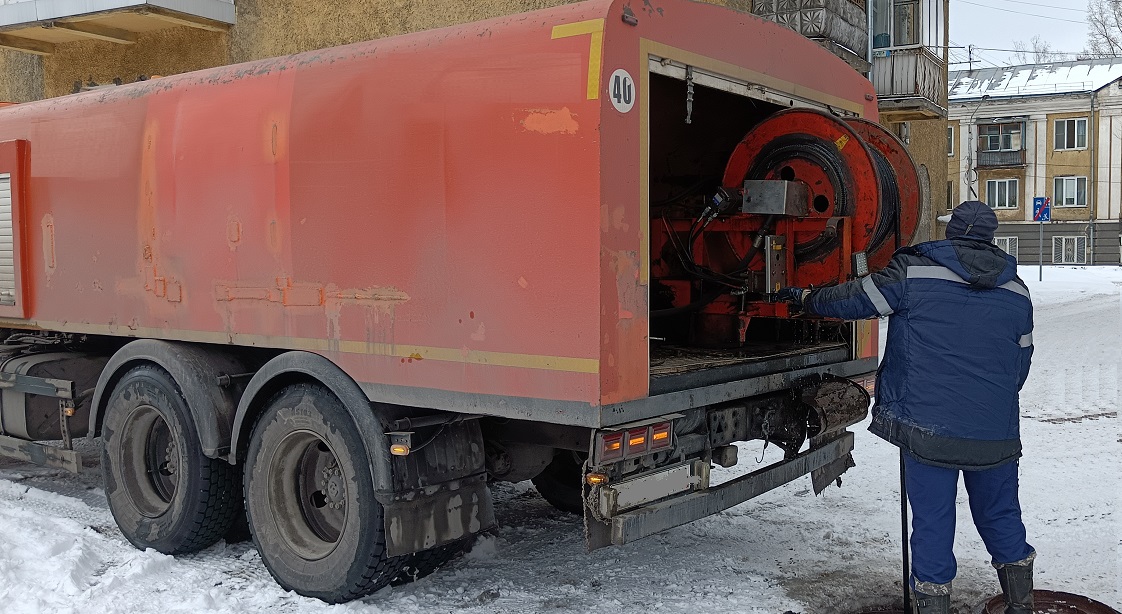 Каналопромывочная машина и работник прочищают засор в канализационной системе в Советском